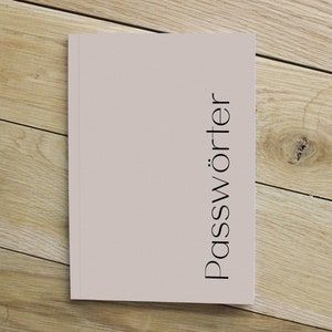 May include: A light pink notebook with the word "Passwörter" printed in black on the front cover.