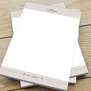 Puede incluir: Una pila de papel para bloc de notas beige y blanco con la palabra "Notizen" en la parte superior y el texto "dream plan. do." en la parte inferior.