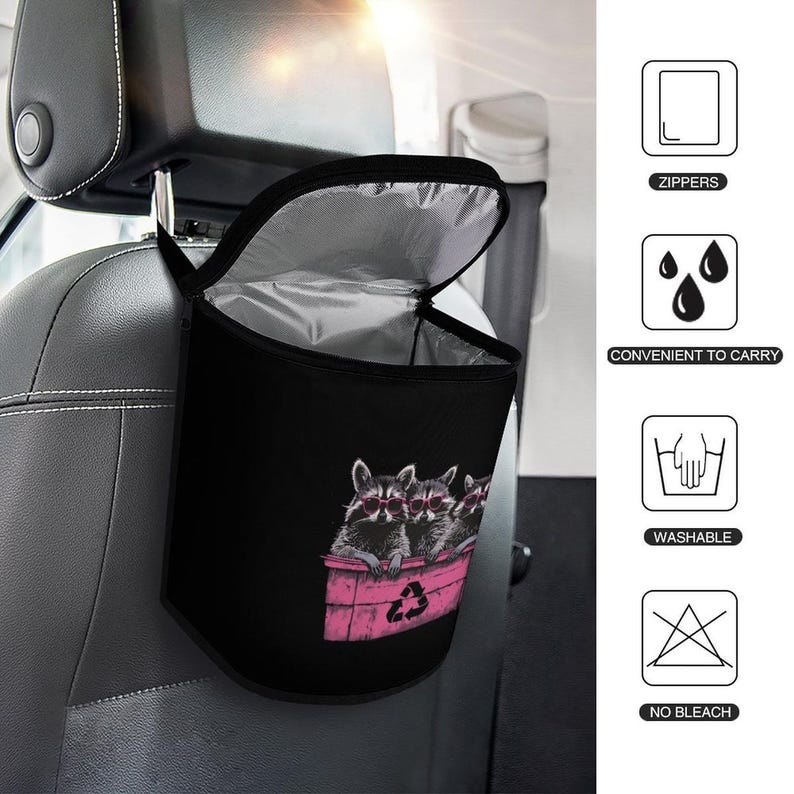 May include: Black car trash bag with a raccoon design. The bag features a pink trash bin with three raccoons wearing sunglasses. The bag hangs from the headrest of a car seat and has a zippered top.