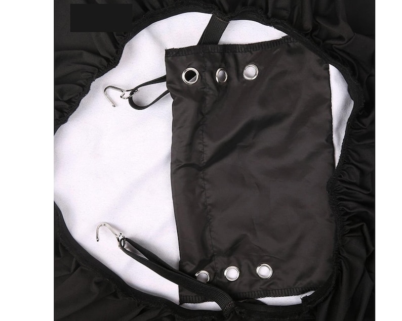 May include: Black car seat cover with elastic straps and a built-in pocket. The cover has a white fleece lining and multiple metal grommets.