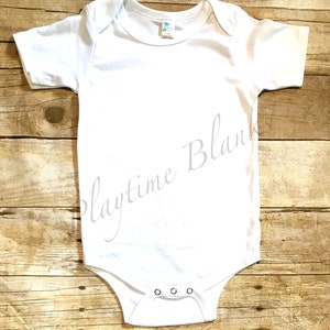 May include: White baby onesie with short sleeves and snap closures. The onesie is blank and ready for customization.