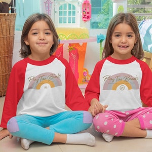 May include: Two children wearing red and white baseball shirts with a rainbow and the text "Play Time Blanks" printed on the front. The children are sitting on the floor with their legs crossed.
