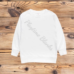 May include: A white crew neck sweatshirt with long sleeves. The text "Playtime Blanks" is printed diagonally across the front in a light gray color. The sweatshirt is displayed on a wooden background.