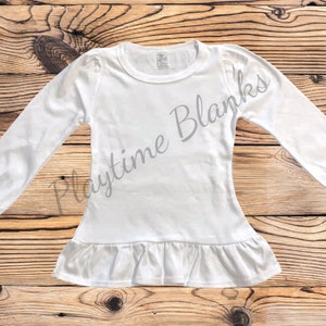 May include: White long-sleeve shirt with a ruffled hem. The shirt is made of a soft, comfortable fabric and has a relaxed fit.