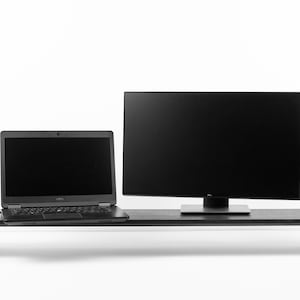 Puede incluir: Un soporte de monitor de madera negro con un portátil y un monitor en la parte superior. También hay una taza de café negra y una pequeña planta en maceta en el soporte.