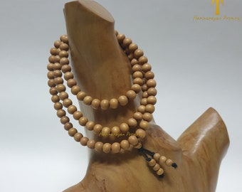 May include: A wooden mala or prayer beads with a brown color. The beads are strung on a cord and are displayed on a wooden stand.