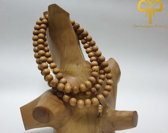 May include: A wooden mala bead necklace with 108 beads, displayed on a wooden stand. The beads are a light brown color and the stand is a darker brown color.