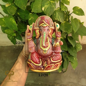 May include: A pink and gold Ganesha statue with intricate details. The statue is 22 cm tall and 12 cm wide. The statue is made of stone and has a traditional Indian design.