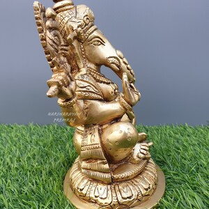Puede incluir: Una estatua de bronce dorada de Ganesha, el dios hind&uacute; de la sabidur&iacute;a y la prosperidad, sentado sobre una base de loto. La estatua est&aacute; intrincadamente detallada y tiene un dise&ntilde;o tradicional.