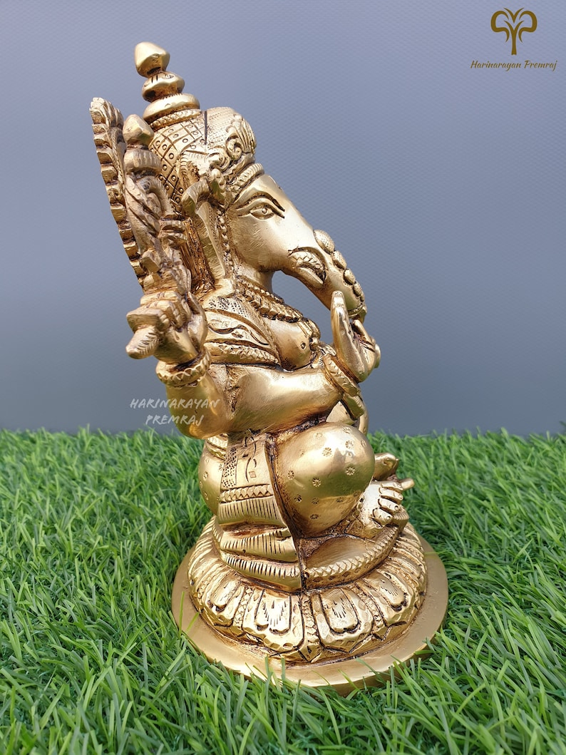 Puede incluir: Una estatua de bronce dorada de Ganesha, el dios hind&uacute; de la sabidur&iacute;a y la prosperidad, sentado sobre una base de loto. La estatua est&aacute; intrincadamente detallada y tiene un dise&ntilde;o tradicional.