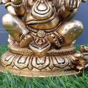 Puede incluir: Una estatua de bronce dorada de Ganesha, el dios hind&uacute; de la sabidur&iacute;a y la prosperidad, sentado sobre una base de loto. La estatua est&aacute; intrincadamente detallada y presenta a Ganesha con su trompa levantada y sosteniendo un dulce en su mano. Un peque&ntilde;o rat&oacute;n est&aacute; sentado en la base de la estatua.