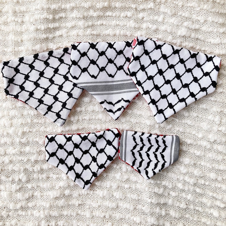 May include: A collection of six white and black patterned bandanas with a red lining. The bandanas feature a geometric design with black diamond shapes and a gray and white striped pattern. The bandanas are arranged on a white textured surface.