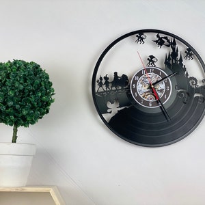 May include: Black vinyl record clock with a silhouette design of a group of people walking across a bridge with a castle in the background. The clock face has Roman numerals and a red second hand.