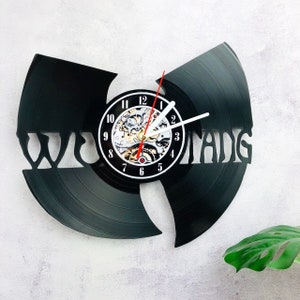 May include: A black vinyl record clock with a Wu-Tang Clan logo and a clock face with a skeletonized clock mechanism.