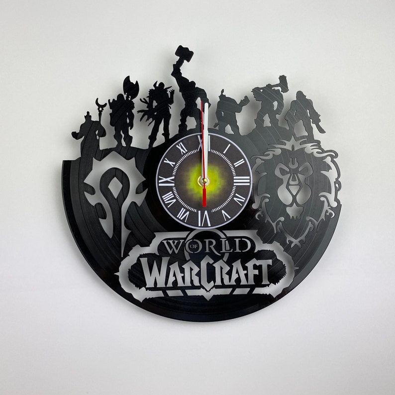 Puede incluir: Reloj de vinilo negro con personajes del videojuego World of Warcraft. La esfera del reloj tiene n&uacute;meros romanos y un dise&ntilde;o en blanco y negro. El reloj est&aacute; rodeado de personajes del juego, incluyendo un le&oacute;n, un guerrero y un mago.