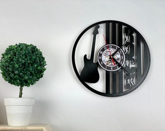 Könnte beinhalten: Schwarze Schallplattenuhr mit einer Silhouette einer E-Gitarre und dem Wort "ROCK" in einer stilisierten Schrift. Das Zifferblatt ist ein kleinerer Kreis mit römischen Ziffern.