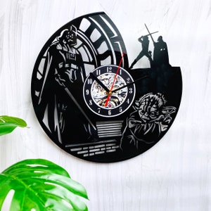 May include: Black vinyl record clock featuring Star Wars characters Darth Vader, Yoda, and Luke Skywalker. The clock has a black background with a silver clock face and black hands.