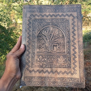 Op de afbeelding: Een bruin leren dagboek met een reliëf van een Keltische levensboom. Het dagboek heeft een decoratieve rand met ingewikkelde patronen.