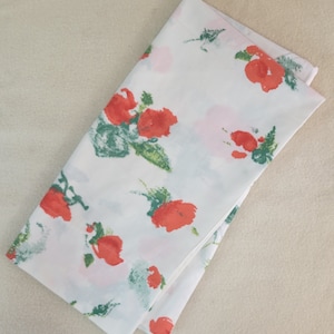 May include: White fabric with a floral pattern. The flowers are red and green and have a watercolor-like appearance.