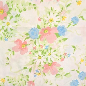 May include: A white fabric with a floral pattern featuring pink, blue, yellow, and white flowers. Green leaves and stems intertwine among the blooms. The design is a repeating pattern of various flower types.