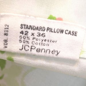 May include: Close-up of a white pillowcase label with the text "STANDARD PILLOW CASE" and measurements of 42 x 36 inches. The label also indicates a 50% polyester and 50% cotton blend, with the JCPenney brand.