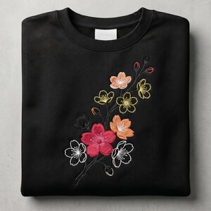 May include: Black crewneck sweatshirt featuring an embroidered floral design. The embroidery includes flowers in shades of red, orange, yellow, and white, with black and green accents. The sweatshirt is folded neatly.