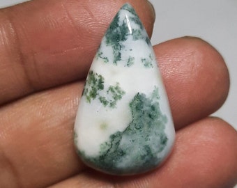 Op de afbeelding: Een druppelvormige edelsteen met een witte basis en groene, mosachtige insluitsels. De gepolijste steen heeft een glad oppervlak en een glanzende afwerking, die de natuurlijke patronen benadrukt.