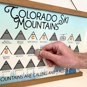 May include: A colorful poster with a list of Colorado ski mountains. The poster is framed in wood and has the text "COLORADO SKI MOUNTAINS" at the top. The poster also has the text "MOUNTAINS ARE CALLING AND I MUST GO" at the bottom.