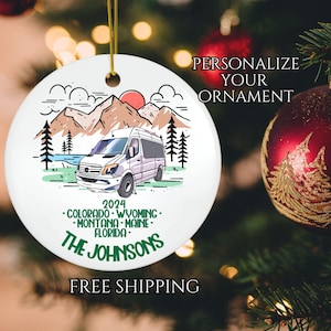 May include: White ceramic Christmas ornament with a cartoon illustration of a white van in a mountain landscape. The ornament includes the text "2024", "Colorado", "Wyoming", "Montana", "Maine", "Florida", and "The Johnsons".