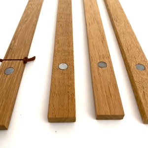 May include: Four wooden magnetic picture hanging strips with silver metal magnets on each end. The strips are light brown and have a natural wood grain.