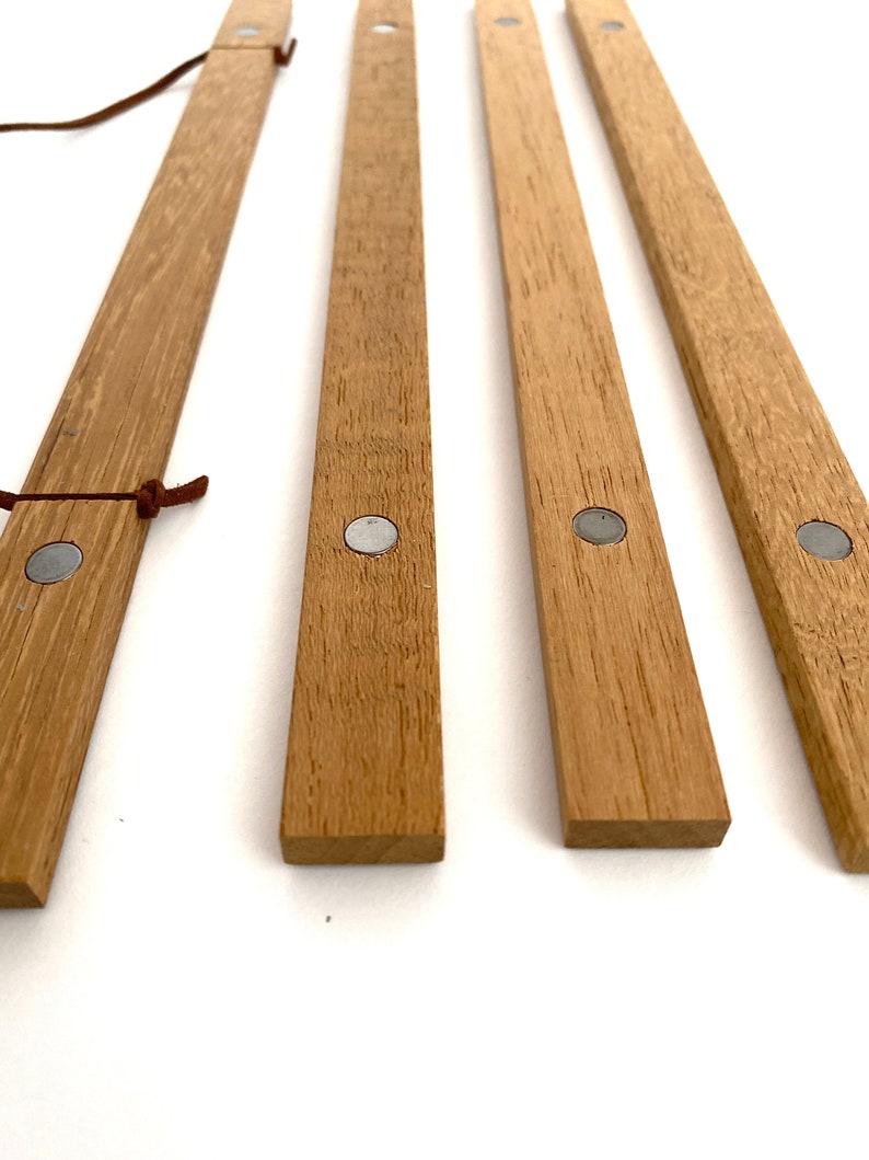 May include: Four wooden magnetic picture hanging strips with silver metal magnets on each end. The strips are light brown and have a natural wood grain.