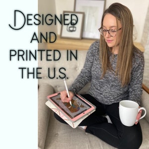 May include: A person is seated, holding a white mug and a tablet with a stylus. The tablet displays a map design. The text "Designed and Printed in the U.S." is visible in the image.