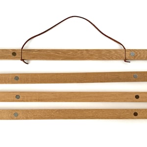 May include: Four wooden rods with a brown leather cord attached to the top rod. Each rod has a silver magnetic button on either end.