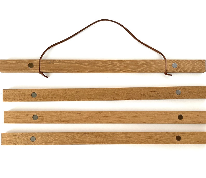 May include: Four wooden rods with a brown leather cord attached to the top rod. Each rod has a silver magnetic button on either end.