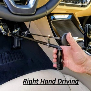 Puede incluir: Un dispositivo de control manual negro instalado en un coche para conducir con la mano derecha. El dispositivo está conectado a los pedales y a la columna de dirección. El texto "Right Hand Driving" se muestra en la parte inferior de la imagen.