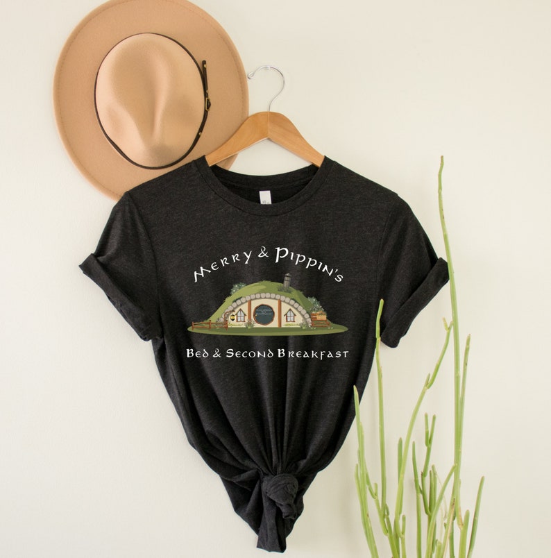 May include: A dark gray t-shirt with a white graphic of a hobbit hole with the text "Merry & Pippin's Bed & Second Breakfast".