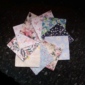 May include: A collection of fabric squares featuring a variety of floral patterns in shades of pink, blue, and white. The squares are arranged in a circular pattern, creating a visually appealing design.