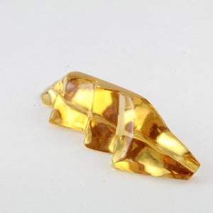 May include: A yellow, faceted, glass sculpture with a jagged, abstract shape.