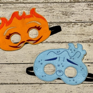 May include: Two felt masks, one orange with flames and a face, the other blue with water droplets and a face.