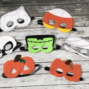 May include: Set of eight felt Halloween masks. The masks are in various colors and designs, including a skull, a ghost, a mummy, a pumpkin, a Frankenstein, and a candy corn. The masks are all attached to black elastic bands.
