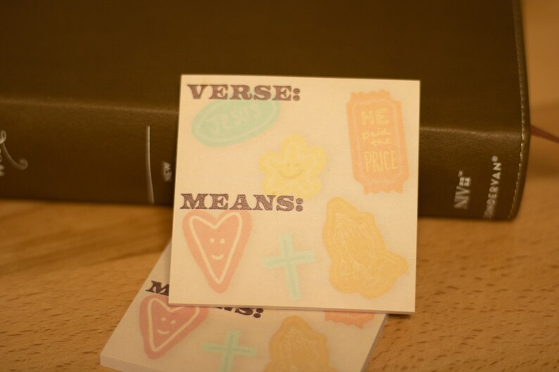 May include: Two beige sticky notes with the words "VERSE: MEANS:" printed on them. The notes are decorated with various hand-drawn images, including hearts, stars, and a ticket with the words "The Price" on it.