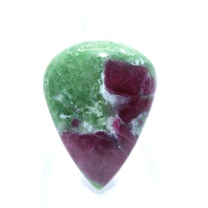 May include: A green and pink gemstone cabochon with a teardrop shape. The gemstone has a mottled pattern of green, pink, and white.