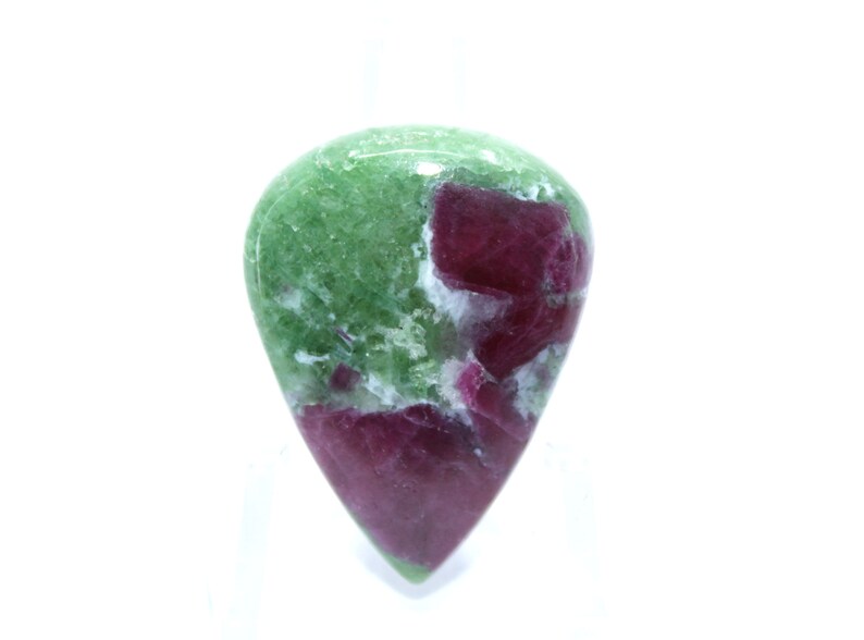 May include: A green and pink gemstone cabochon with a teardrop shape. The gemstone has a mottled pattern of green, pink, and white.