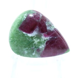 May include: A green and red gemstone cabochon with a teardrop shape. The gemstone has a mottled pattern of green and red.