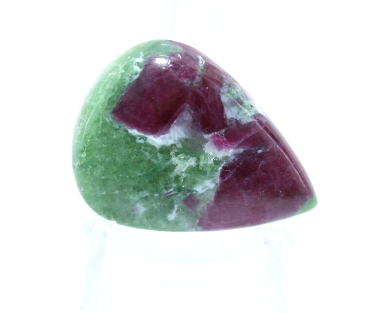 May include: A green and red gemstone cabochon with a teardrop shape. The gemstone has a mottled pattern of green and red.