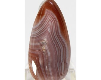 May include: A teardrop-shaped agate cabochon with a brown, white, and pink banded pattern.