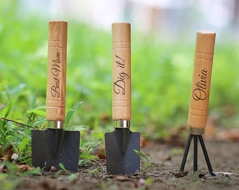 May include: Three gardening tools with wooden handles. The handles are engraved with the words "Best Mom", "Dig it!" and "Olivia".
