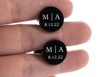 Puede incluir: Dos gemelos negros con una inscripción blanca. La inscripción dice "M|A 8.12.22".