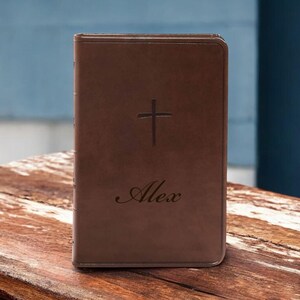 May include: A brown leather-bound journal with a cross and the name "Alex" embossed on the front cover.