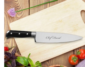 Puede incluir: Un cuchillo de chef con mango negro y las palabras "Chef David" grabadas en la hoja, descansando sobre una tabla de cortar de madera. El cuchillo está rodeado de albahaca fresca, tomates y un tazón de madera de tomates.